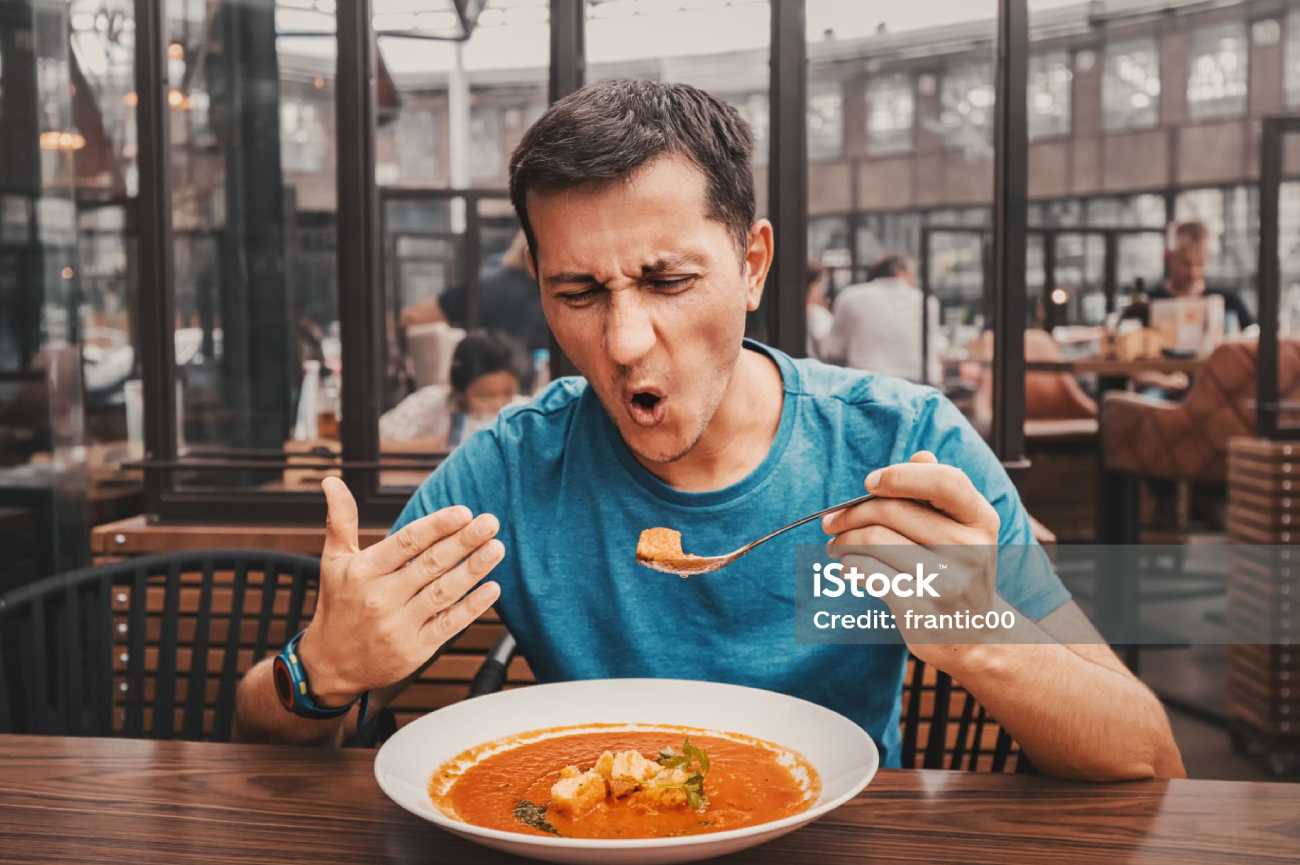 Homem comendo um prato de sopa quente.